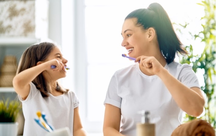 Mother and daughter having fun as they brush their teeth together