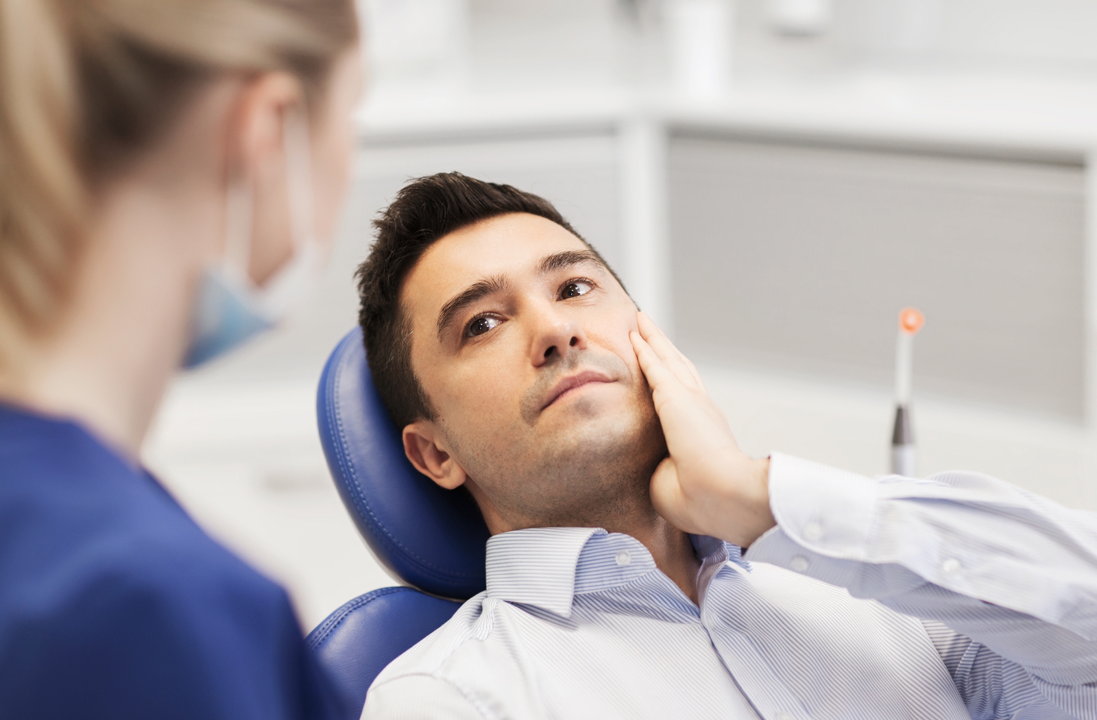 male patient with toothache complaining to female dentist at dental clinic office