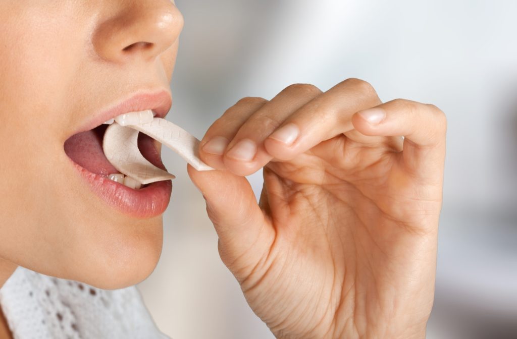 A woman putting a stick of chewing gum into her mouth