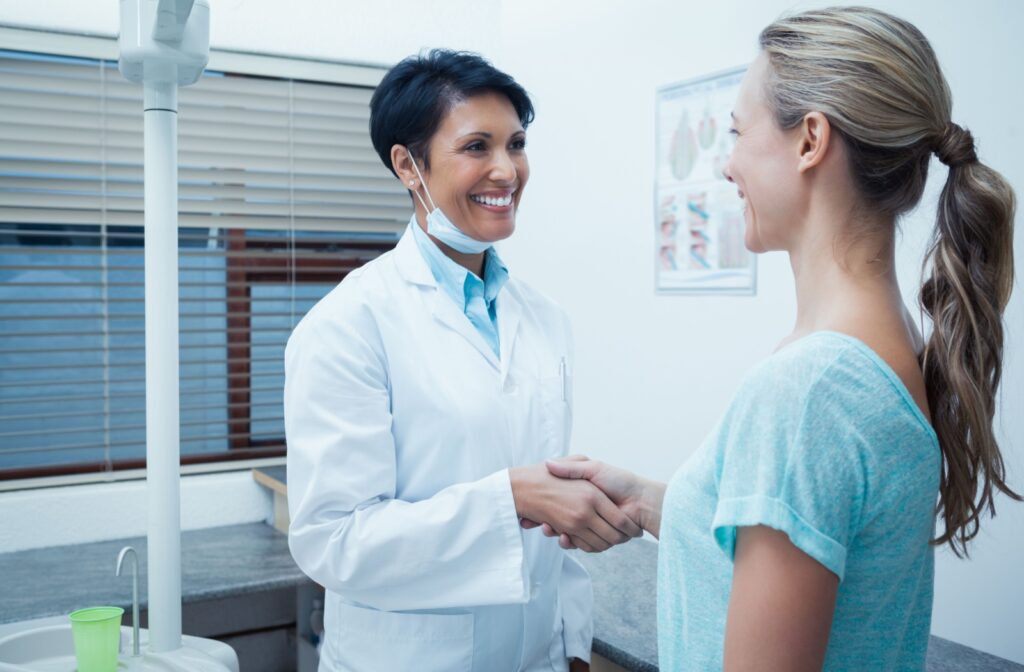 A woman in an dentist's office shaking hands with her dentist
