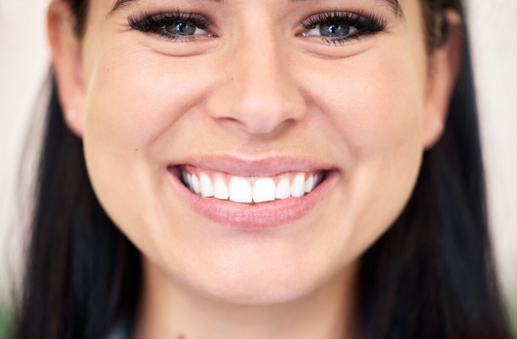 A woman smiling and showing her straight teeth after Invisalign treatment.
