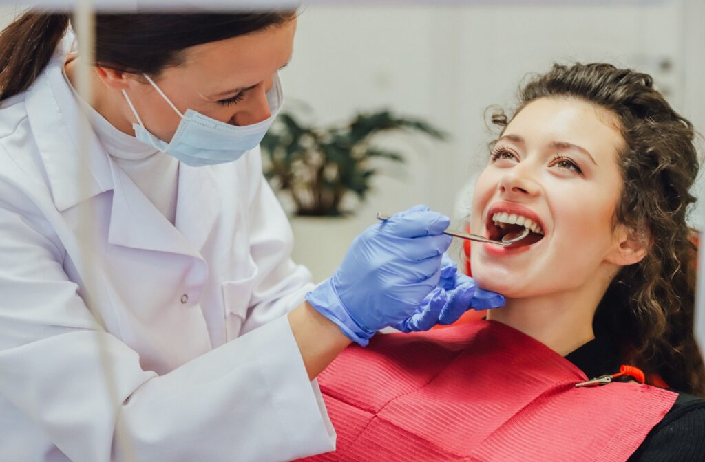 A person smiling as they have a checkup with their dentist to take care of their veneers.