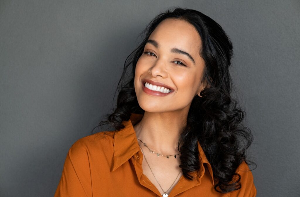 A young adult smiling confidently after a dental visit, feeling great about her oral health after receiving Oralvital treatment.