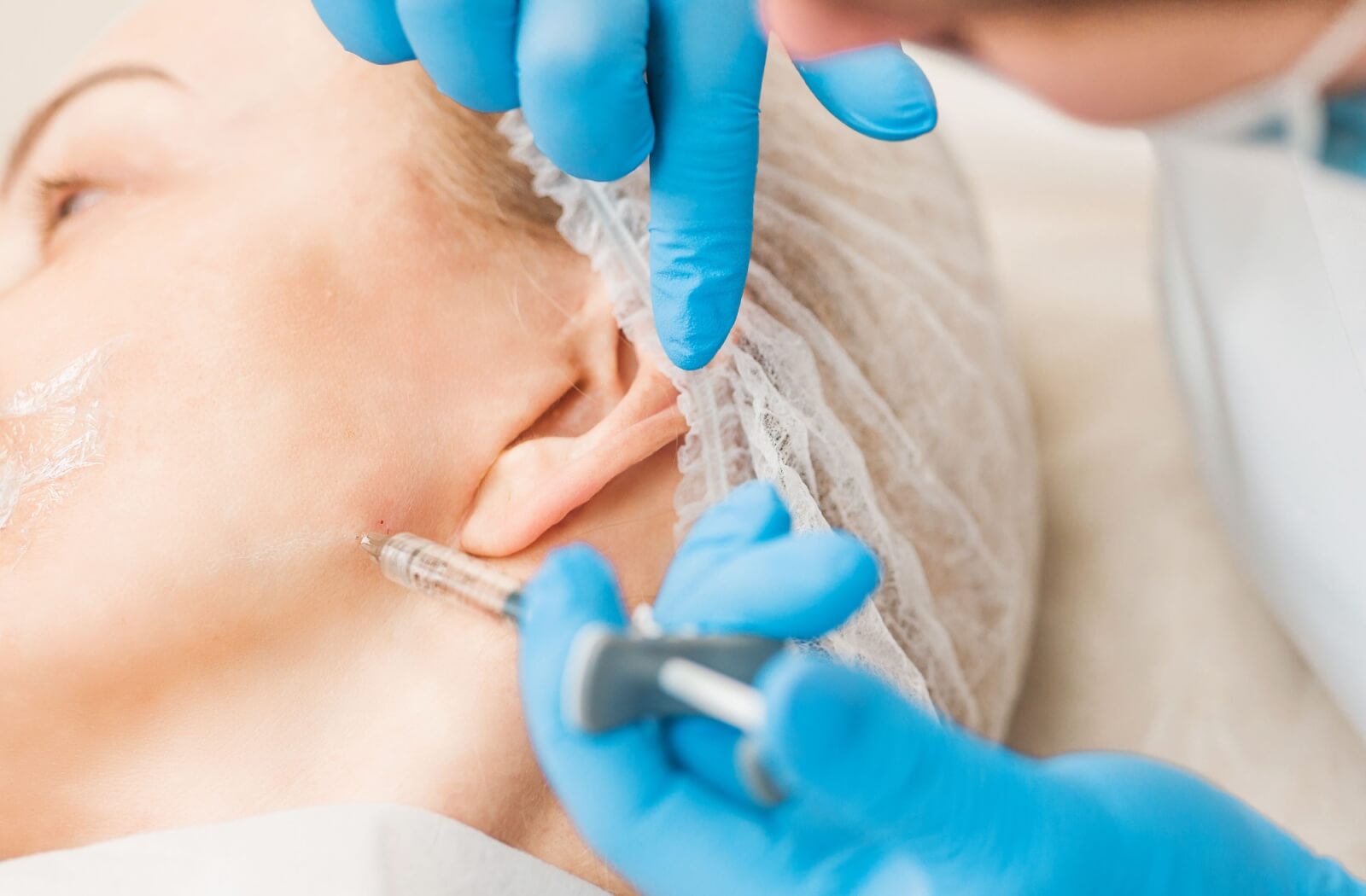 A dentist carefully injects Botox into a patient's jaw for TMJ treatment.